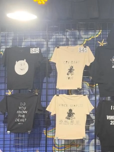 Front and back views of the cream Cry Baby Tour tee and black devil graphic tee